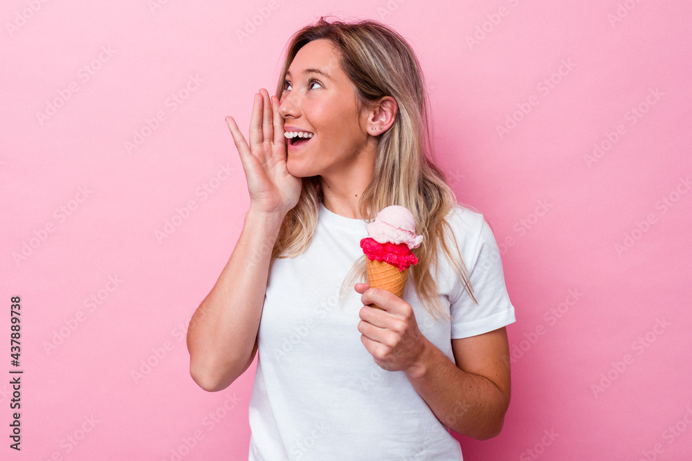 Young australian woman holding an ice cream isolated on pink background shouting and holding palm near opened mouth. Young australian woman holding an ice cream isolated on pink background shouting and holding palm near opened mouth.