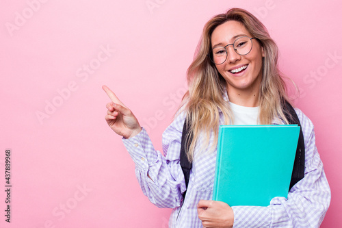 Young student australian woman isolated on pink background smiling and pointing aside, showing something at blank space.