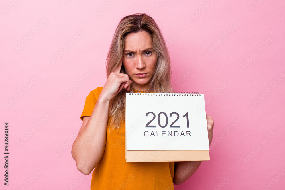 Young australian woman holding a calendar isolated on pink background pointing temple with finger, thinking, focused on a task. Young australian woman holding a calendar isolated on pink background pointing temple with finger, thinking, focused on a task.