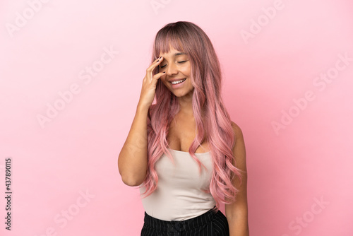 Young mixed race woman with pink hair isolated on pink background smiling a lot