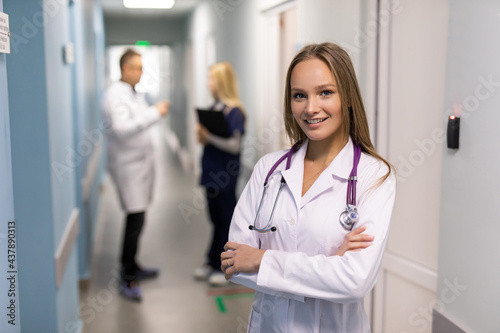 Portrait of a young woman doctor in a clinic with colleagues in the background