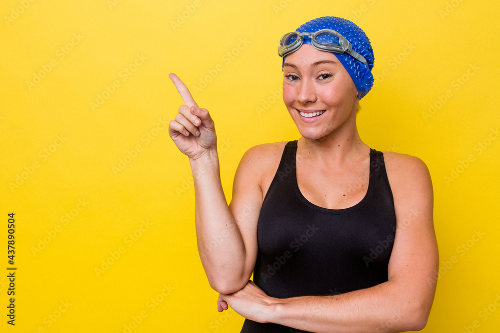 Young australian swimmer woman isolated on yellow background smiling cheerfully pointing with forefinger away. Young australian swimmer woman isolated on yellow background smiling cheerfully pointing with forefinger away.