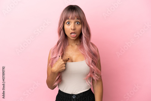 Young mixed race woman with pink hair isolated on pink background pointing to oneself