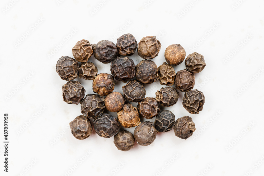 several hainan black peppercorns close up on gray several hainan black peppercorns close up on gray