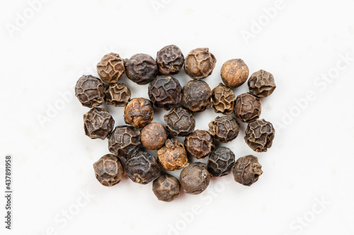 several hainan black peppercorns close up on gray