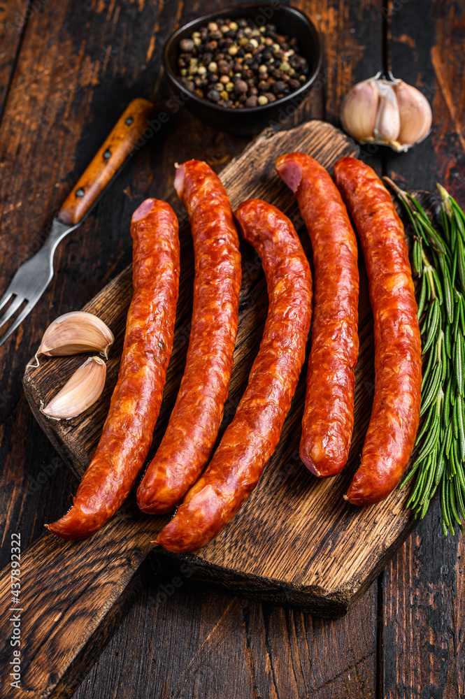 Hot Smoked sausages with addition of fresh aromatic herbs and spices. Dark wooden background. Top view