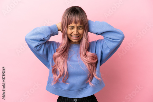 Young mixed race woman with pink hair isolated on pink background frustrated and covering ears © luismolinero