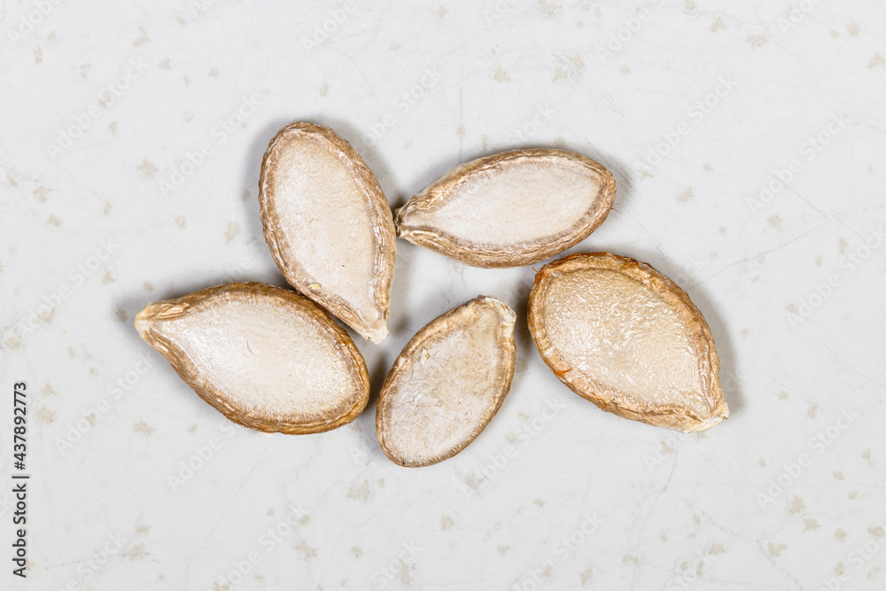 several whole pumpkin seeds close up on gray several whole pumpkin seeds close up on gray