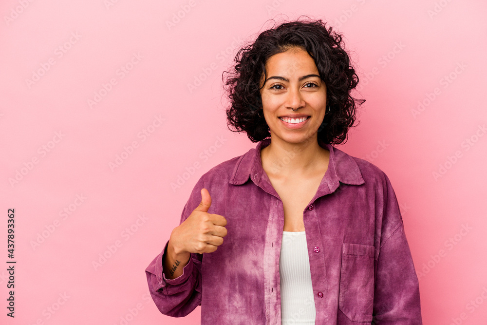 Young curly latin woman isolated on pink background smiling and raising thumb up Young curly latin woman isolated on pink background smiling and raising thumb up