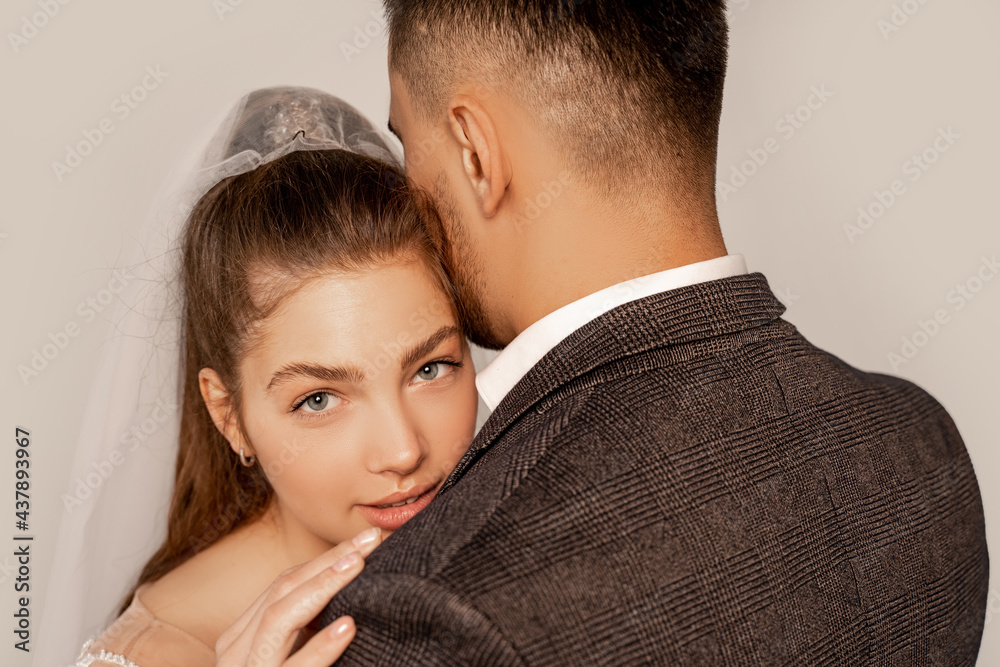 charming bride looking at camera while embracing man isolated on grey charming bride looking at camera while embracing man isolated on grey