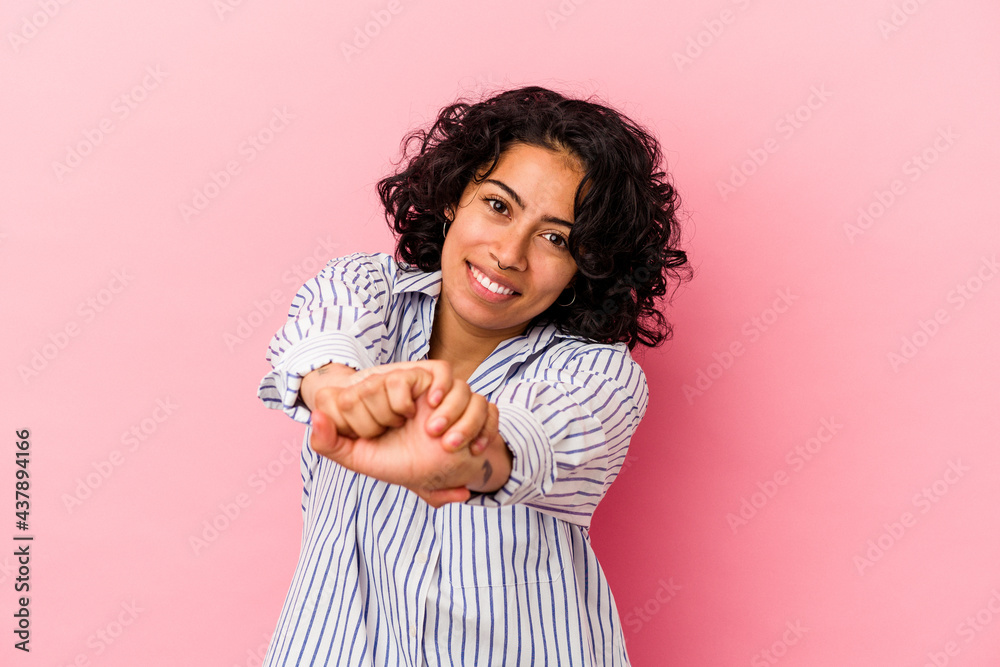 Young curly latin woman isolated on pink background stretching arms, relaxed position. Young curly latin woman isolated on pink background stretching arms, relaxed position.