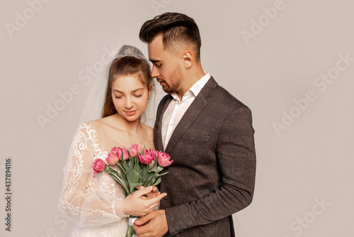 young man near charming bride with fresh tulips isolated on grey