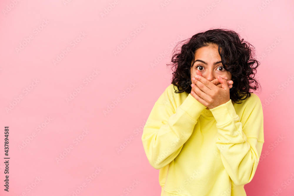 Young curly latin woman isolated on pink background thoughtful looking to a copy space covering mouth with hand. Young curly latin woman isolated on pink background thoughtful looking to a copy space covering mouth with hand.