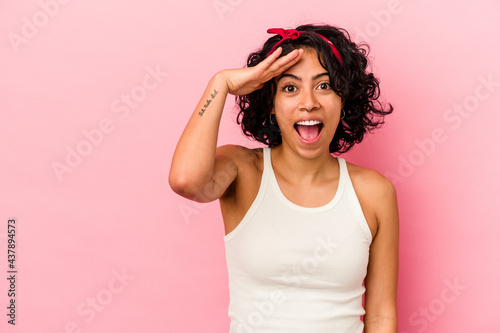 Young curly latin woman isolated on pink background shouts loud, keeps eyes opened and hands tense.