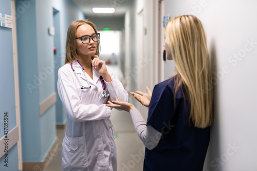 Medical Staff Talking In Hospital Corridor With Digital Tablet