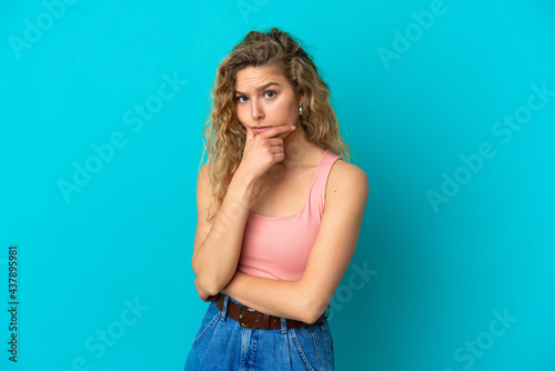 Young blonde woman isolated on blue background having doubts © luismolinero