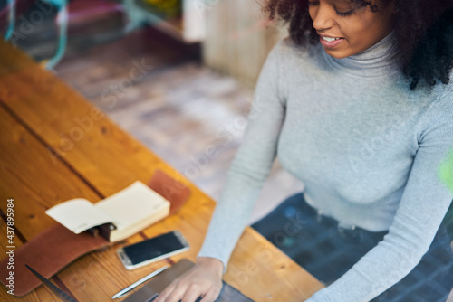 Crop black woman using laptop during break in modern workspace