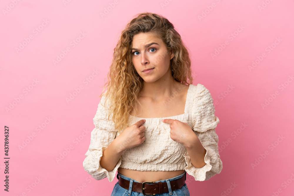 Young blonde woman isolated on pink background pointing to oneself