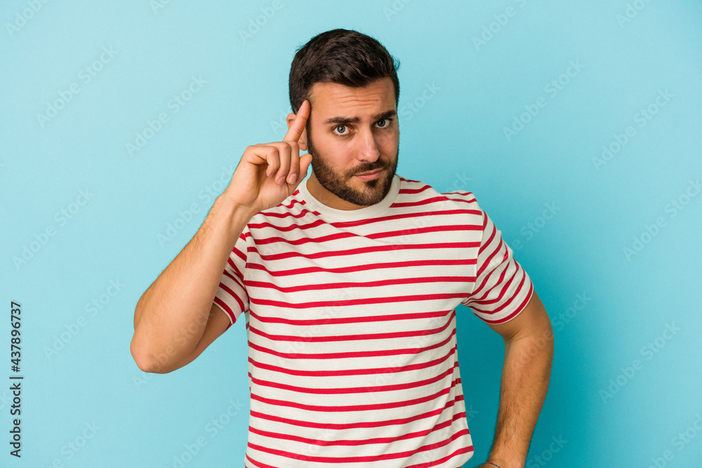 Young caucasian man isolated on blue background pointing temple with finger, thinking, focused on a task. Young caucasian man isolated on blue background pointing temple with finger, thinking, focused on a task.