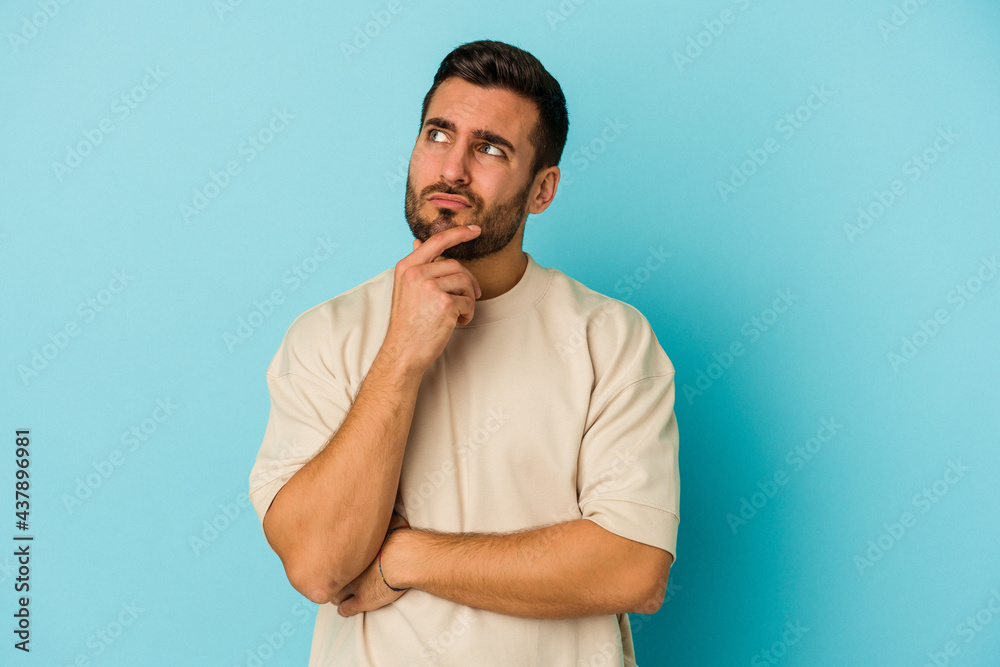 Young caucasian man isolated on blue background thinking and looking up, being reflective, contemplating, having a fantasy. Young caucasian man isolated on blue background thinking and looking up, being reflective, contemplating, having a fantasy.