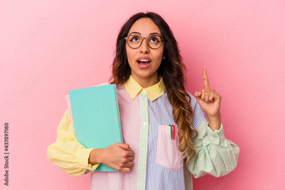 Young student mexican woman isolated on pink background pointing upside with opened mouth. Young student mexican woman isolated on pink background pointing upside with opened mouth.