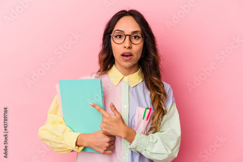 Young student mexican woman isolated on pink background pointing to the side