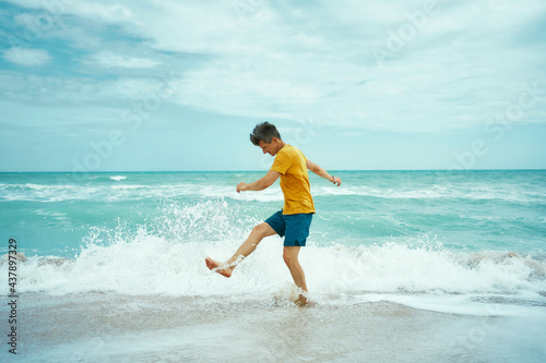 Cheerfulness man having fun at sea or ocean beach, splashing water