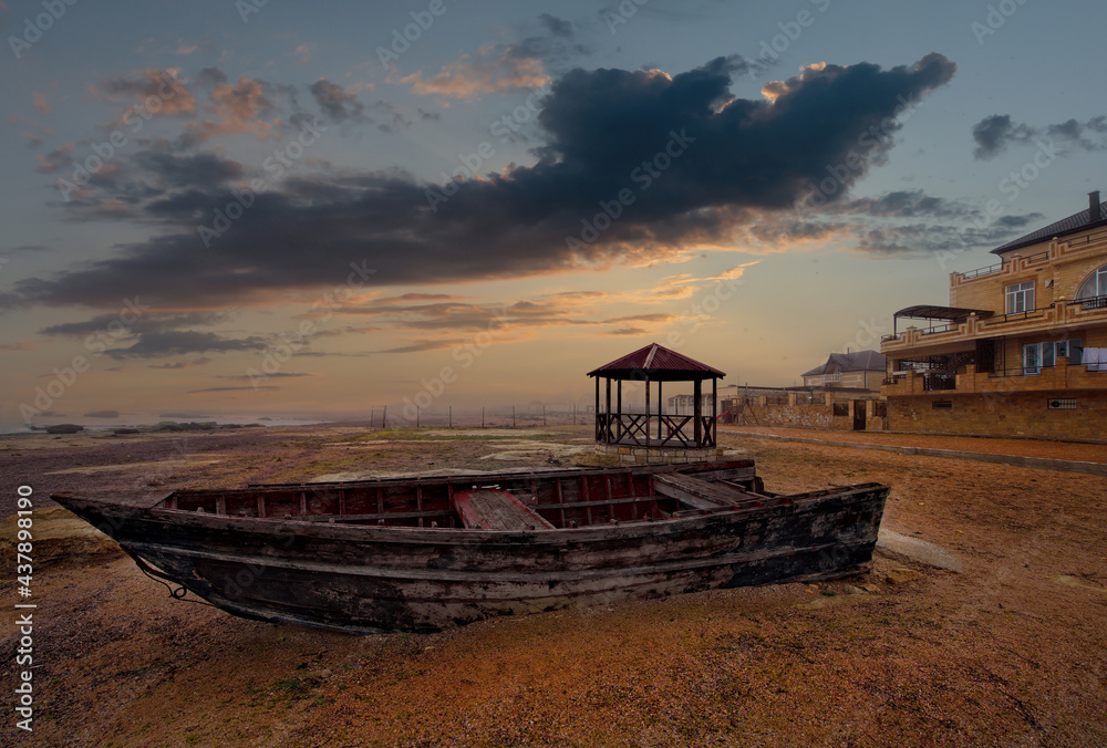Russia. Republic of Dagestan. Early morning on the Western shore of the Caspian Sea. An old wooden boat on the sandy beach of a coastal hotel on the northern outskirts of Makhachkala.