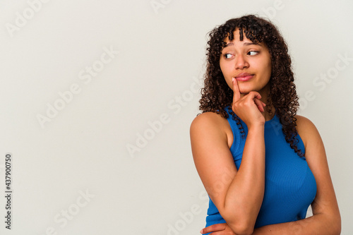 Young mixed race woman isolated on white background looking sideways with doubtful and skeptical expression.