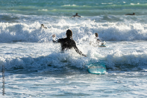 Surfer joins his friends surfing in the waves. Surf in Mediterranean coast. Image with sunset lights and selective focus.