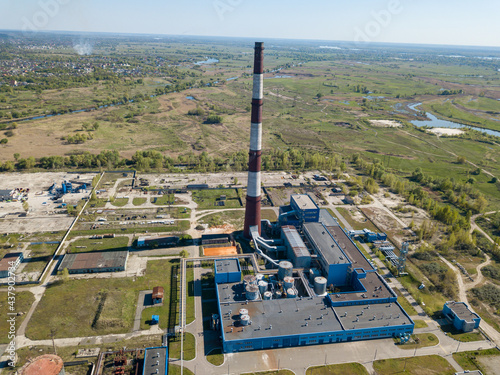 High chimney of a power plant on the outskirts of the city. Green spring steppe on the background. Aerial drone view. photo