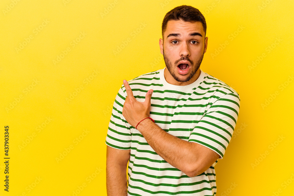 Young caucasian man isolated on yellow background pointing to the side Young caucasian man isolated on yellow background pointing to the side