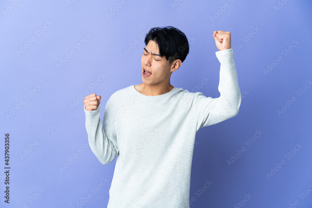 Young Chinese man isolated on purple background celebrating a victory Young Chinese man isolated on purple background celebrating a victory