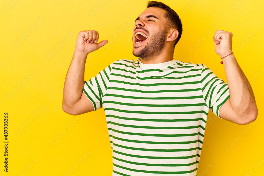 Young caucasian man isolated on yellow background raising fist after a victory, winner concept. Young caucasian man isolated on yellow background raising fist after a victory, winner concept.