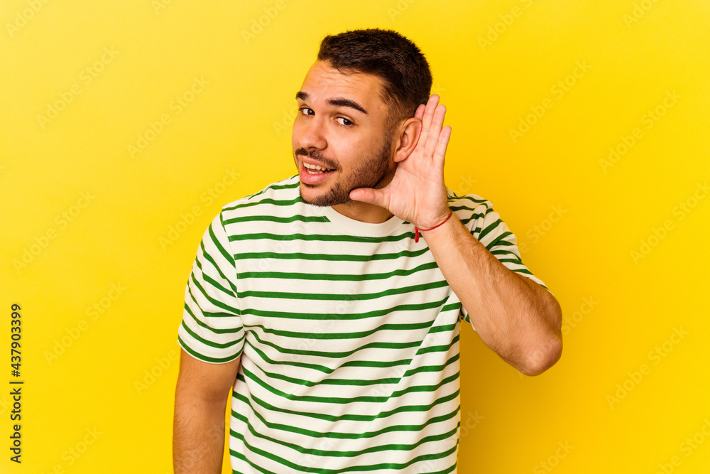 Young caucasian man isolated on yellow background trying to listening a gossip. Young caucasian man isolated on yellow background trying to listening a gossip.