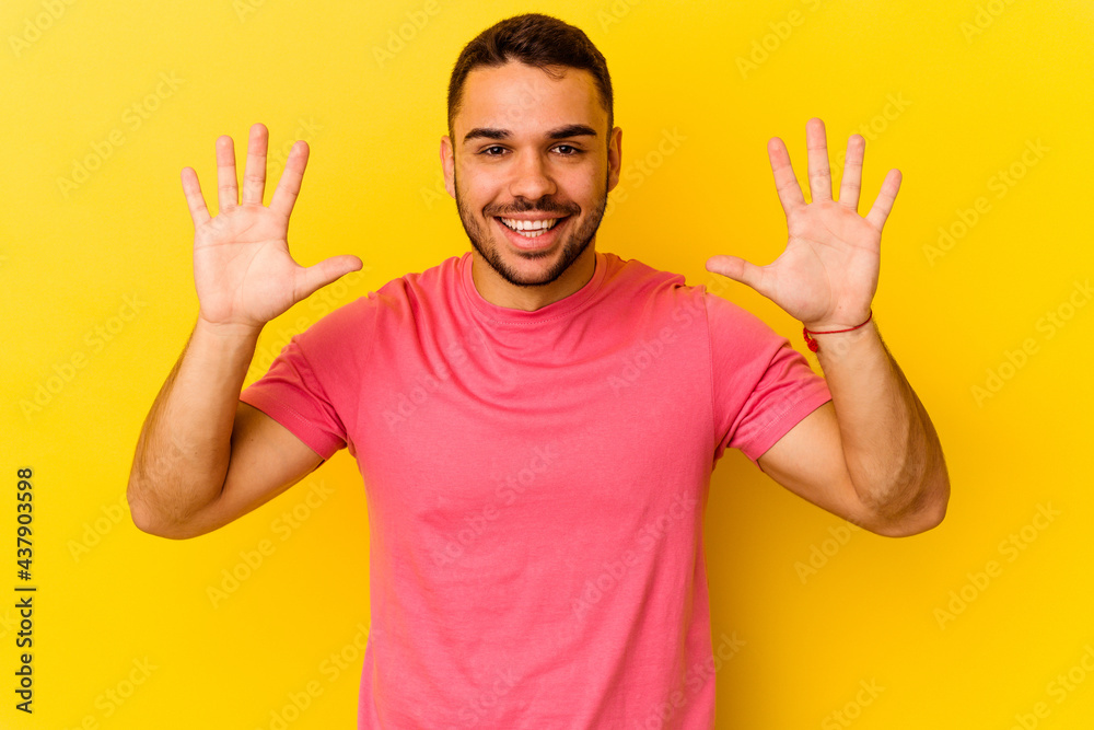 Young caucasian man isolated on yellow background showing number ten with hands. Young caucasian man isolated on yellow background showing number ten with hands.