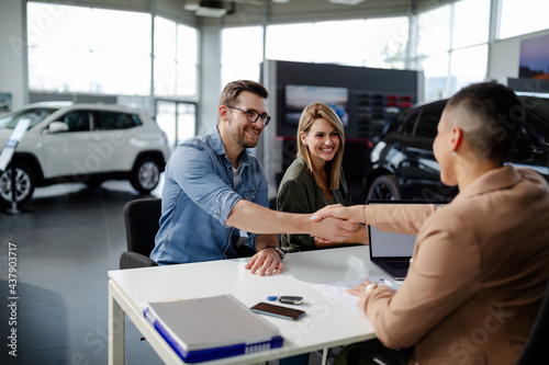 Male customer and female car dealer shaking hands at showroom. photo