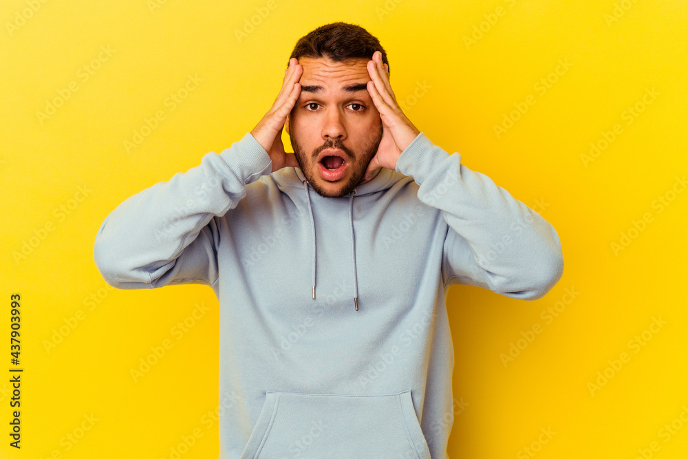 Young caucasian man isolated on yellow background having fun covering half of face with palm. Young caucasian man isolated on yellow background having fun covering half of face with palm.