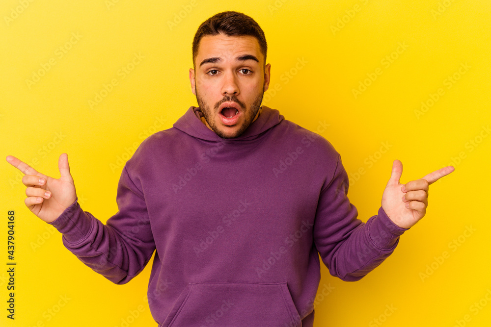 Young caucasian man isolated on yellow background pointing to different copy spaces, choosing one of them, showing with finger. Young caucasian man isolated on yellow background pointing to different copy spaces, choosing one of them, showing with finger.