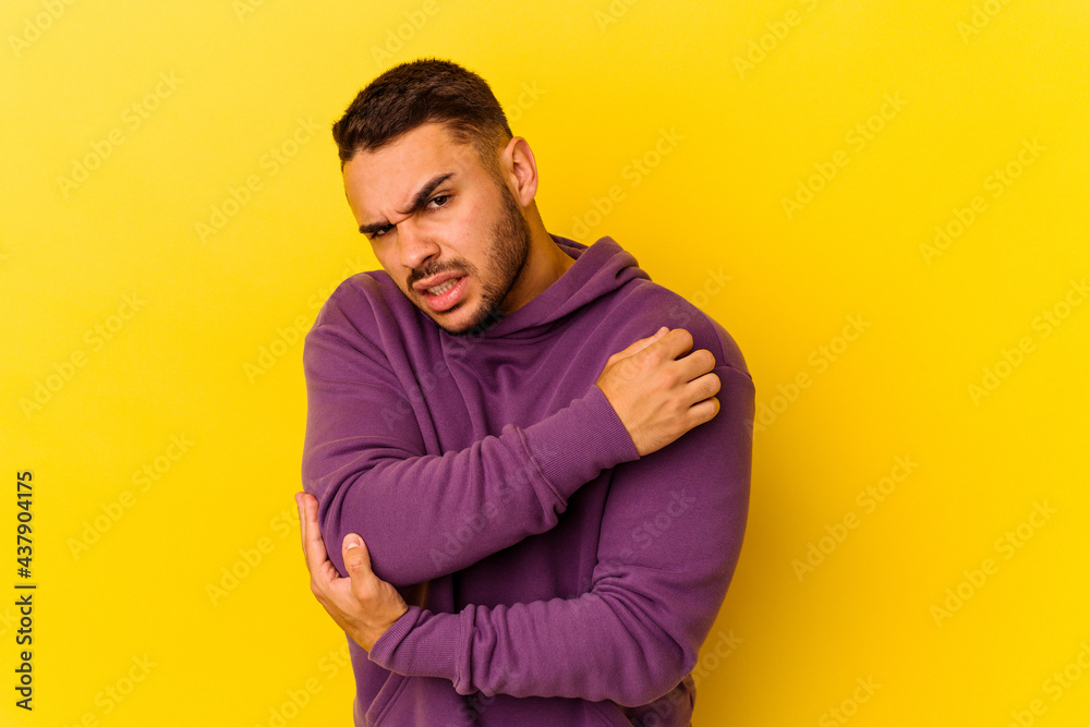 Young caucasian man isolated on yellow background massaging elbow, suffering after a bad movement. Young caucasian man isolated on yellow background massaging elbow, suffering after a bad movement.