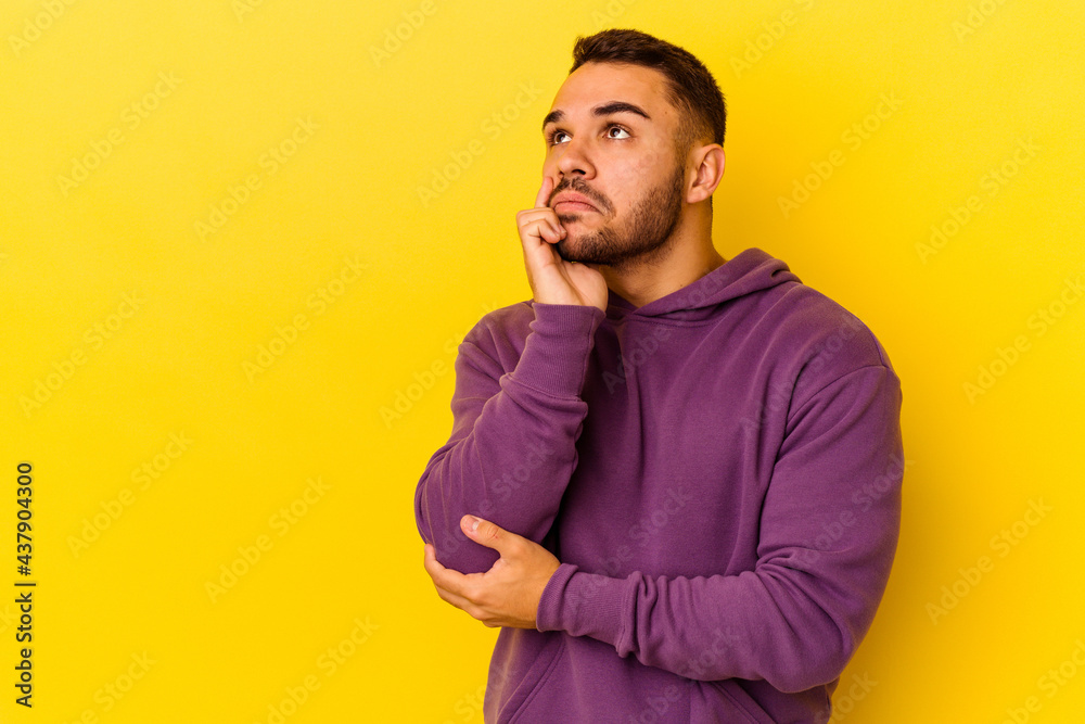 Young caucasian man isolated on yellow background looking sideways with doubtful and skeptical expression. Young caucasian man isolated on yellow background looking sideways with doubtful and skeptical expression.