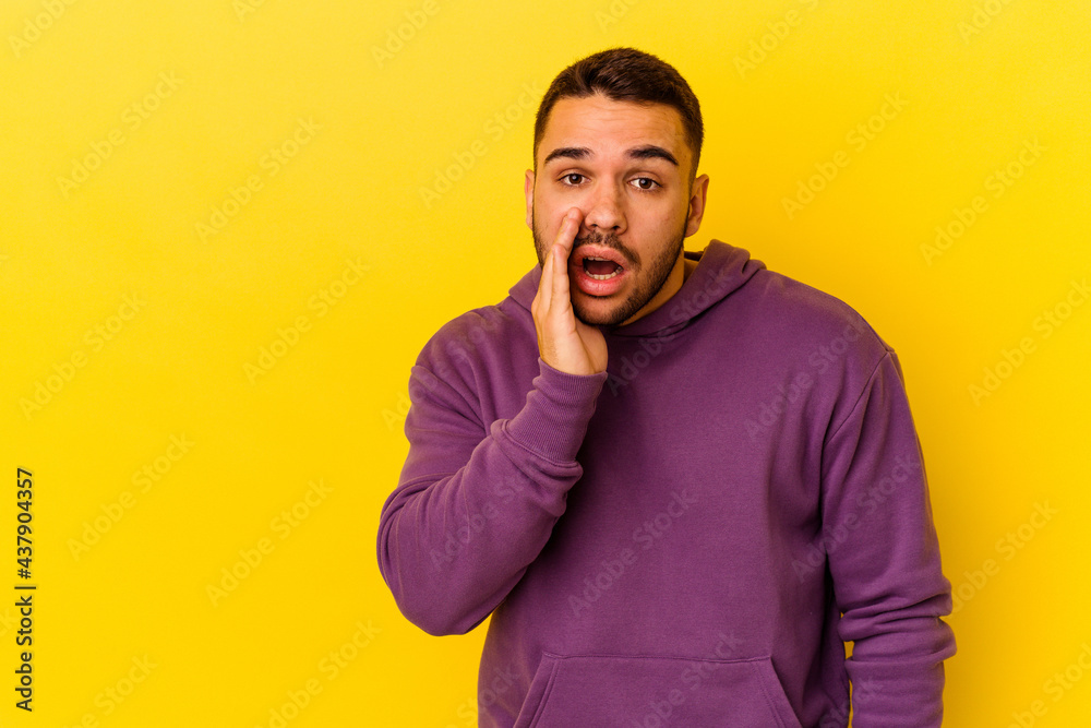 Young caucasian man isolated on yellow background is saying a secret hot braking news and looking aside Young caucasian man isolated on yellow background is saying a secret hot braking news and looking aside