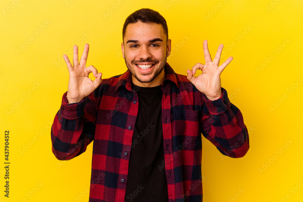 Young caucasian man isolated on yellow background cheerful and confident showing ok gesture. Young caucasian man isolated on yellow background cheerful and confident showing ok gesture.