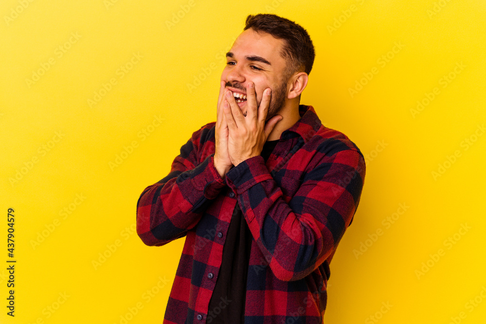 Young caucasian man isolated on yellow background laughing about something, covering mouth with hands.