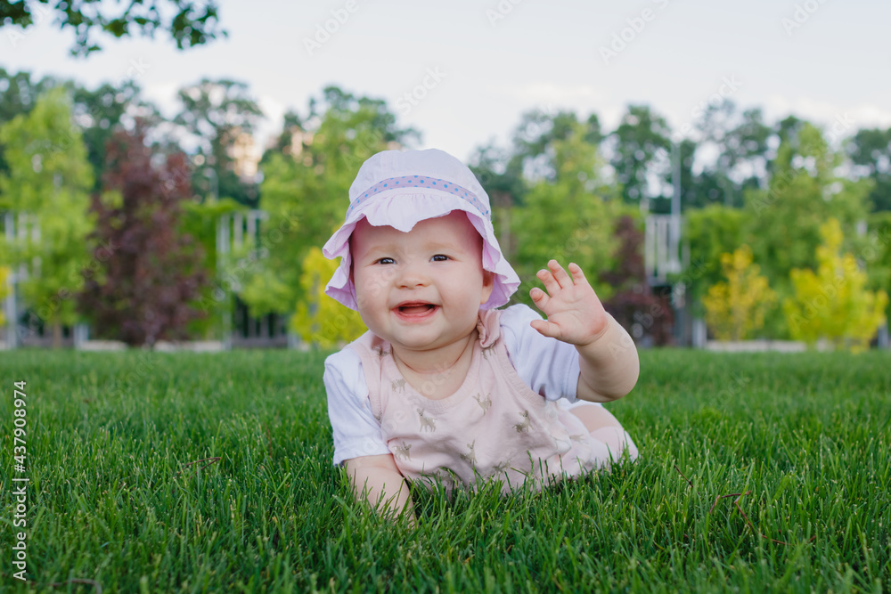 Cute 8 months old newborn nursing baby girl lying on the grass in the park and smiling on a summer sunny day. Place for text. Cute 8 months old newborn nursing baby girl lying on the grass in the park and smiling on a summer sunny day. Place for text.