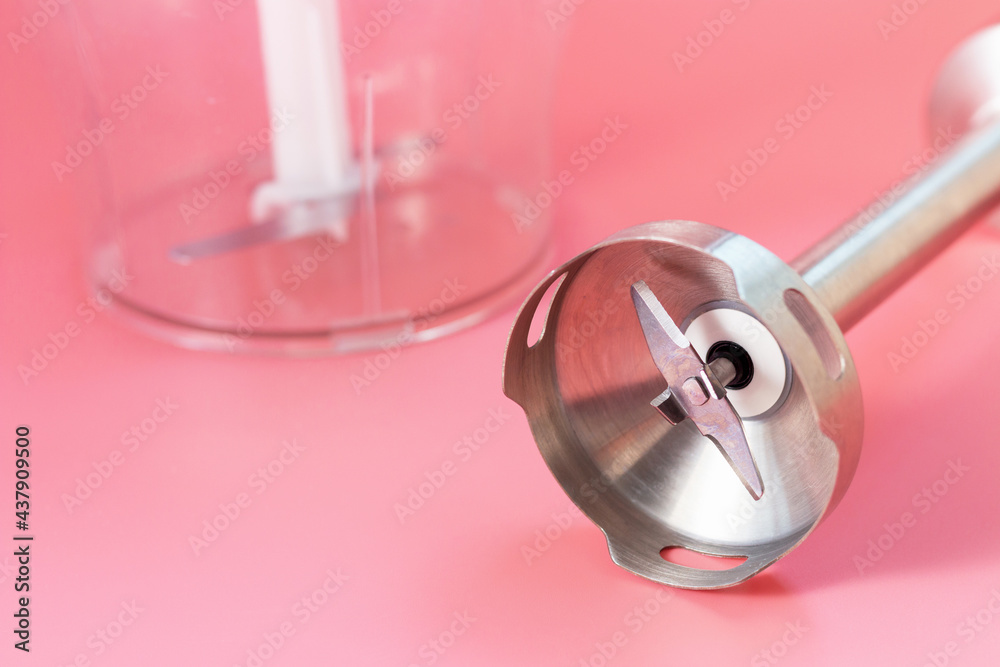 Steel hand blender and the bowl on pink background close-up.