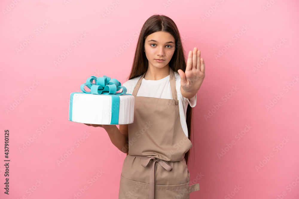 Little girl with a big cake over isolated pink background making stop gesture Little girl with a big cake over isolated pink background making stop gesture