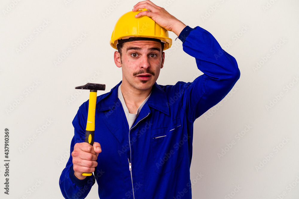 Young caucasian worker man holding a hammer isolated on white background being shocked, she has remembered important meeting. Young caucasian worker man holding a hammer isolated on white background being shocked, she has remembered important meeting.