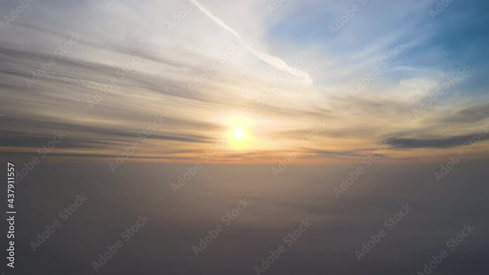 Aerial view of vibrant yellow sunrise over white dense clouds with blue sky overhead. Aerial view of vibrant yellow sunrise over white dense clouds with blue sky overhead.