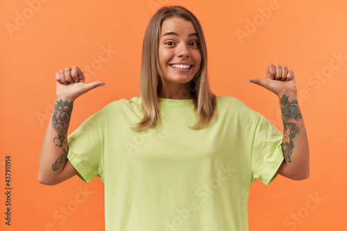 Canvastavla Cheerful pretty young woman in yellow tshirt smiling and pointing at herself by